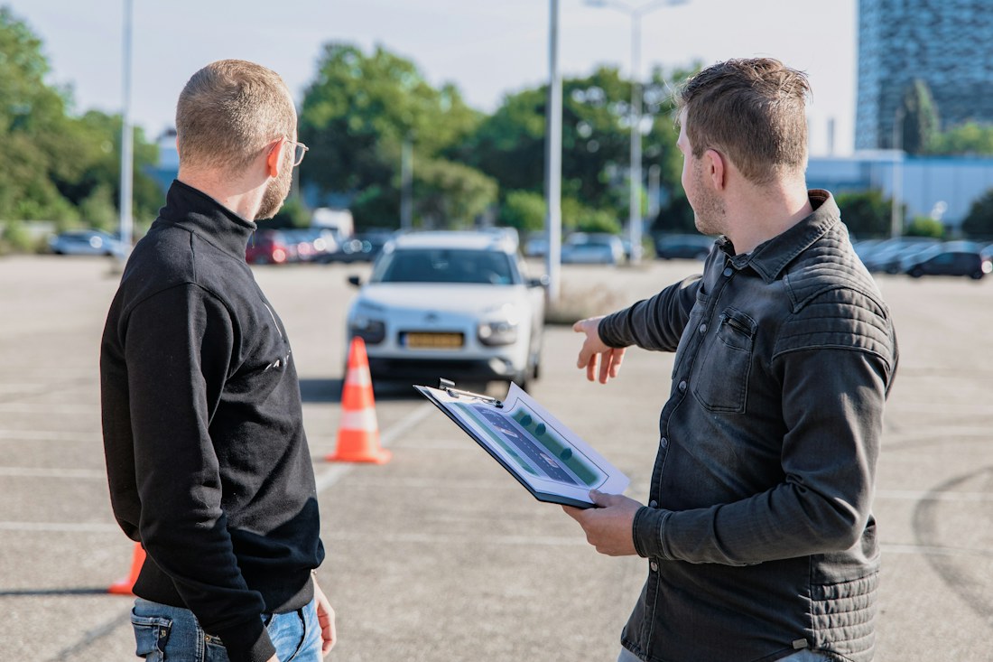 Driving instructor discussing a lesson beside a learner car